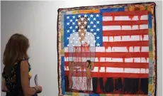  ?? — AFP file photo ?? A visitor watches the work of US artist Faith Ringgold, ‘The Flag is Bleeding #2’ (1997), during a preview on December 4, 2019 ahead of the opening the following day of the Art Basel internatio­nal fair that takes place annually in Miami Beach the first week of December.