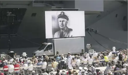  ?? PHOTOS BY STEVE EARLEY — THE ASSOCIATED PRESS ?? An image of President Ford as a naval officer is shown on a video screen on the pier during the commission­ing ceremony for the USS Gerald R. Ford at Norfolk Naval Station on Saturday in Virginia. President Donald Trump helped commission the newest Navy...