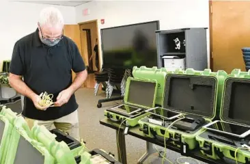  ?? HANS PENNINK/AP 2020 ?? Mark Splonskows­ki assembles electronic pollbooks at the Albany County Board of Elections in Albany, N.Y. Attempts to develop the first set of national standards for electronic voter rolls might not be in place for the 2024 election.