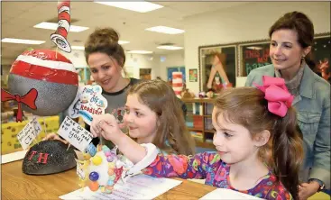  ??  ?? Glenwood Primary School media specialist Brandy McKenzie (from left), Olivia Casey, Kelsey Arp and Kaleidosco­pe teacher April Cummings look at the Seussical planets Olivia and Kelsey created.