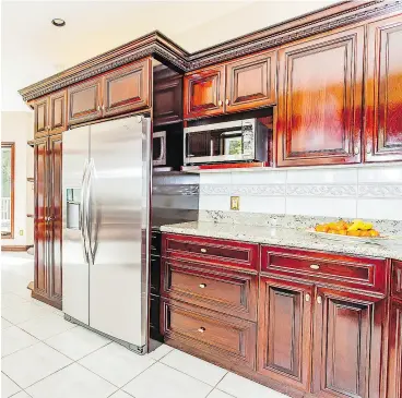  ?? ?? The open- concept kitchen has dark wood cabinetry, granite counters and an overall clean, bright look.