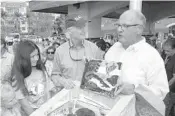  ?? ROB O’NEAL/AP ?? U.S. Sen. Rick Scott, center, watches as Rafael Penalver, right, preservati­onist and board president of Key West’s San Carlos Institute, prepares to place artwork in the island’s bicentenni­al time capsuleon March 25.