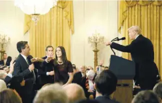  ??  ?? A White House staff member reaches for the microphone held by Acosta as he questions Trump on Wednesday.