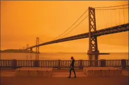  ?? BRITTANY HOSEA-SMALL/AFP VIA GETTY IMAGES ?? A person walks along the Embarcader­o under an orange smoke-filled sky in San Francisco on Sept. 9, 2020.