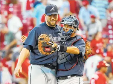  ?? THE ASSOCIATED PRESS ?? Atlanta Braves relief pitcher Jim Johnson, left, and catcher Kurt Suzuki celebrate Saturday after closing the 12th inning of their game against the Reds in Cincinnati. The Braves won 6-5.