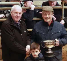  ??  ?? Denis Kehoe of Kehoe Brothers presenting the winning cup to Sean Tobin, 1st best two or more non-continenta­l butchers type heifer, pictured with Ciaran Cullen.