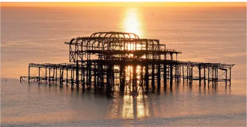  ?? FOTOS: ANDREAS DROUVE/DPA-TMN ?? Wie ein altes Gerippe im Meer: der West Pier im Sonnenunte­rgang