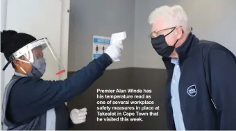  ??  ?? Premier Alan Winde has his temperatur­e read as one of several workplace safety measures in place at Takealot in Cape Town that he visited this week.