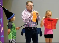  ?? Westside Eagle Observer/MIKE ECKELS ?? Scott Davis puts a pair of handkerchi­efs together with the help of assistant Brooklyn Thompson (right) and apprentice Anthony Sanchez (left) during the “Making Accidents Disappear” magic show at Northside Elementary School in Decatur on Aug. 30.