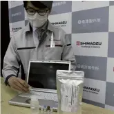  ?? The Yomiuri Shimbun ?? A Shimadzu Corp. official in Kyoto displays a reagent kit capable of detecting the coronaviru­s on surfaces.