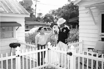  ?? PHOTOS BY JOEY ROULETTE/ORLANDO SENTINEL CORRESPOND­ENT ?? Playing out their daily routine, Clemente Aguirre-Jarquin and his neighbor Derrick Jamison chat and exchange stories over the white picket fences that link their Sunny Center homes in Tampa.