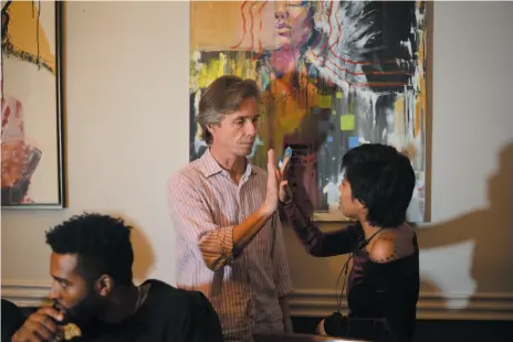  ?? PHOTO FOR THE WASHINGTON POST BY ASTRID RIECKEN ?? David Simpson, left, and 20-year-old Madeleine Hernandez – the woman to whom he is donating a kidney – share a high five during the weekly dinner for young men and women in Washington, D.C.,