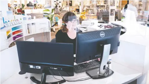  ?? — THE CANADIAN PRESS ?? A receptioni­st wears a visor at a furniture store in St-Jean-sur-Richelieu, Que., on Monday. Retail stores outside the greater Montreal area have been allowed to reopen after forced closure due to COVID-19.