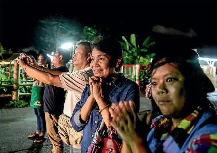  ?? GETTY IMAGES ?? Onlookers watch and cheer as ambulances deliver boys rescued from a cave in northern Thailand to hospital in Chiang Rai.