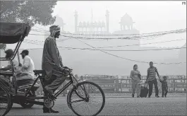  ?? PTI ?? A family crosses a road amid heavy smog in front of the Red Fort in New Delhi on Friday.