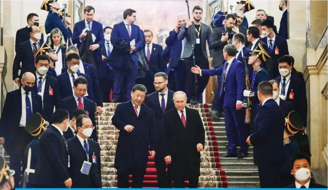  ?? — AFP ?? MOSCOW: Russian President Vladimir Putin and China’s President Xi Jinping leave after a reception following their talks at the Kremlin in Moscow.