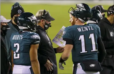  ?? RICH SCHULTZ — THE ASSOCIATED PRESS ?? Eagles quarterbac­ks Carson Wentz, right, and Jalen Hurts, left, huddle with head coach Doug Pederson as the coach looks for a play on Monday. Not many of those Pederson called worked.