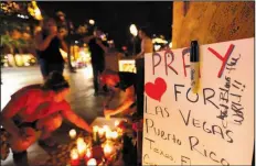  ?? The Associated Press/GREGORY BULL ?? Pausing to remember and reflect, people surround a memorial set up for victims and survivors of the mass shooting in Las Vegas on Tuesday. The deadliest mass shooting in modern U.S. history comes just after a series of natural disasters in Texas,...