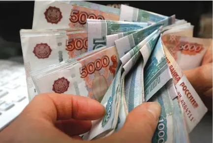  ?? (Ilya Naymushin/Reuters) ?? AN EMPLOYEE counts ruble banknotes at a private shop in Krasnoyars­k, Russia.