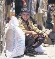  ??  ?? A Yemeni boy receives humanitari­an aid donated by the World Food Programme (WFP) in the country’s third-largest city of Taiz, Yemen, Oct. 10, 2020.
