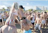  ?? JULIO CORTEZ/AP ?? Cece Guida, right, of New York City, pushes on Sam Reddick, 20, of Evansville, Ind., as spring break revelers look on March 17 in Pompano Beach.