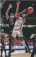  ?? JIM WEBER/NEW MEXICAN FILE PHOTO ?? New Mexico guard Jamal Mashburn Jr. shoots under pressure by UTSA center Jacob Germany on Dec. 10 during a blowout win in The Pit. The Lobos will play in this year’s National Invitation Tournament for their first postseason appearance since the 2013-14 season.