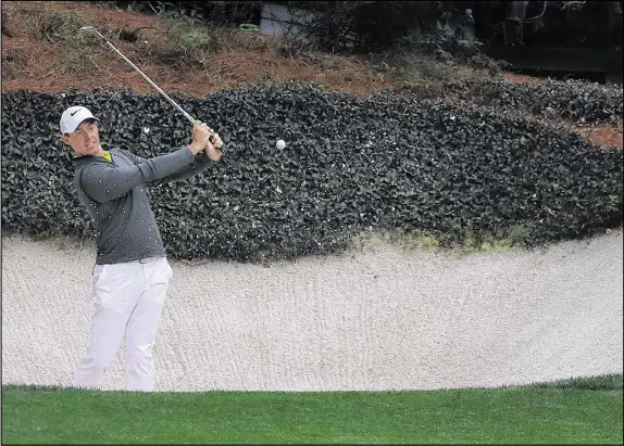  ?? PHOTOS BY CURTIS COMPTON / CCOMPTON@AJC.COM ?? Rory McIlroy blasts from the trap adjacent to the 12th green on Wednesday, one of the 99 practice holes he’s played at Augusta National over the past two weeks. McIlroy enters the week missing only the Masters among major titles.