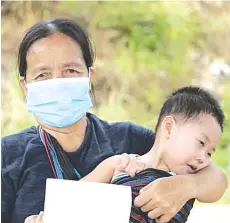  ??  ?? Irip Pang holding her granddaugh­ter and showing the compound issued by the police.