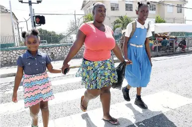  ?? GRINDLEY/CHIEF PHOTO EDITOR NORMAN ?? A parent collects her children from Alpha Primary School in Kingston on Monday when teachers stayed away from the classroom.