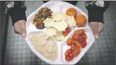  ?? AP PHOTO/WONG MAYE-E ?? A seventh grader carries her plate which consists of three bean chili, rice, mandarins and cherry tomatoes and baked chips during her lunch break at a local public school on Friday in the Brooklyn borough of New York.