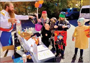  ?? Shelly Thorene / Union Democrat ?? Joetobin, director of the ATCAA Food Bank (above left) in a dapper Prince Charming costume hands out healthy treats to (from left) Emma Ling, 10, Eugene Cesco, 6, Abi Ling, 4, Angelique Cesco, 10, Levi Ling, 6, all of Jamestown, on Friday. ATCAA Communicat­ion Manager Kristy Moore, of Sonora (right), hands a treat to Juliet Lopez, 9, of Sonora.