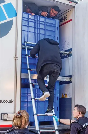  ??  ?? Discovered: Police help the migrants squeeze out of the lorry at a service station