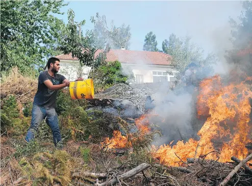  ?? FRANCISCO LEONG / AFP / GETTY IMAGES ?? Locals use buckets to fight a wildfire in Atalaia Fundeira on Monday. More than 2,700 firefighte­rs are still trying to control the blaze in central Portugal that has killed at least 63 people and injured dozens more.