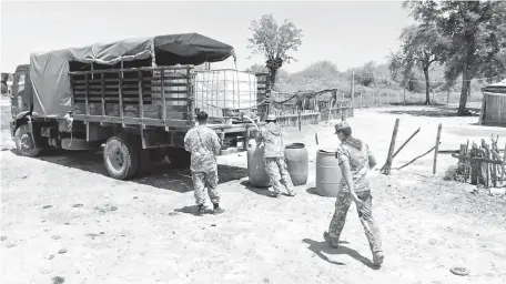  ??  ?? Militares distribuye­n agua a familias de las zonas rurales del Alto Paraguay donde se siente una pronunciad­a sequía.