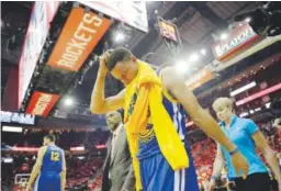  ??  ?? Stephen Curry walks to the Warriors’ locker room Sunday after suffering a knee injury. He will have an MRI on Monday. David J. Phillip, The Associated Press