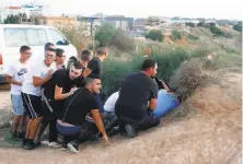  ?? Jack Guez / AFP / Getty Images ?? Young men take cover in the southern Israeli town of Sderot as Hamas militants fire rockets from the Gaza Strip.