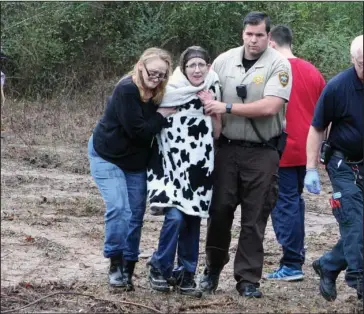  ?? The Sentinel-Record/Richard Rasmussen ?? RESCUED: Carol Morris, left, who lives nearby, and Garland County sheriff’s Deputy Justin Butcher, right, help a woman to a waiting ambulance after she was rescued from the center of the Middle Branch of Gulpha Creek in the 1300 block of Millcreek Road...