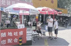  ?? BLOOMBERG ?? People wearing protective masks stand at a health code-screening point outside a market in Beijing, China, last week.