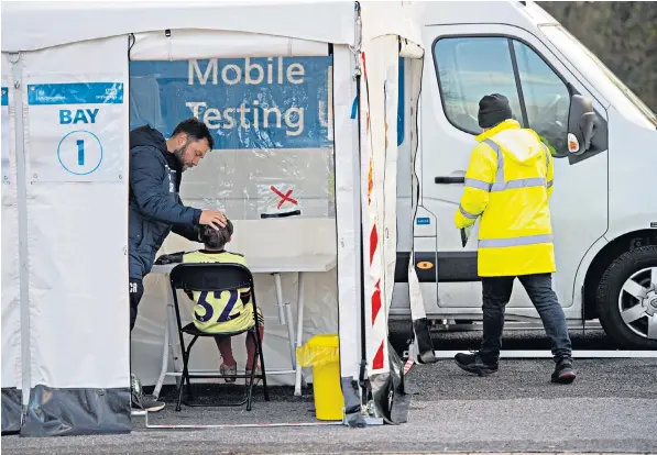  ?? ?? Chris Rowlatt helps his son take a coronaviru­s test in Brentwood after pupils at the town’s Larchwood Primary School were urged to get checked out following an omicron variant scare linked to one class