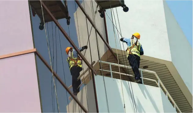  ??  ?? ↑
Workers clean the windows of a highrise. Kamal Kassim/gulf Today