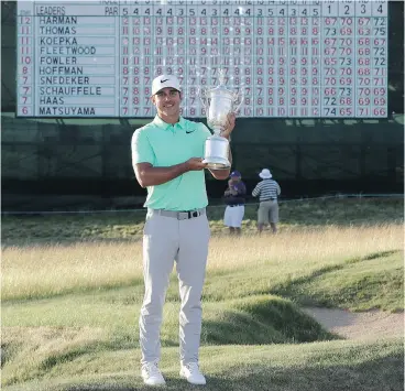  ?? DAVID J. PHILLIP / THE ASSOCIATED PRESS ?? American Brooks Koepka poses with the winning trophy in front of the U. S. Open scoreboard after winning golf ’s second major in Erin, Wis. on Sunday.