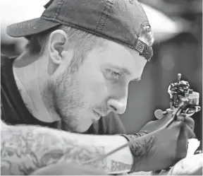  ?? ROBERT HANASHIRO, USA TODAY ?? Tattoo artist Scott Campbell works on a client inside the Shinola store in the Arts District of Los Angeles.