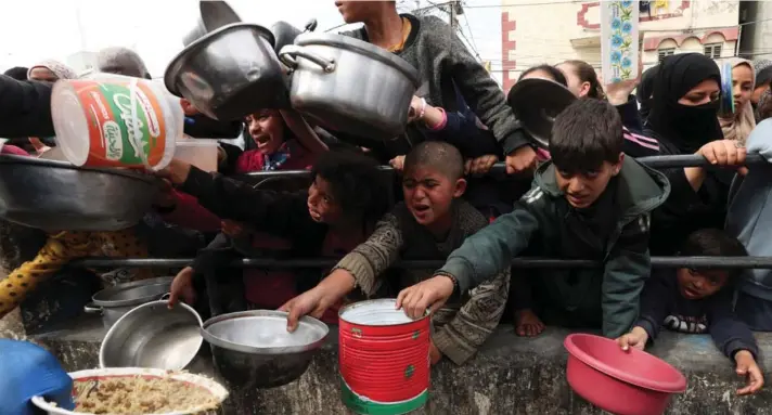  ?? ?? ► Niños palestinos esperan para recibir alimentos de una cocina de caridad en medio de la escasez de suministro­s de alimentos, en Rafah, en el sur de la Franja de Gaza.