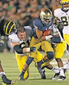  ?? JONATHAN DANIEL/GETTY IMAGES FILES ?? Graham Glasgow of the Wolverines loses his helmet as he tries to tackle Max Redfield of the Fighting Irish at Notre Dame Stadium in 2014. The historical rivalry between the two schools, dormant since 2014, will be rekindled tonight in South Bend, Ind.