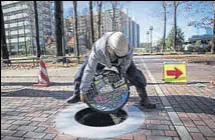  ?? AFP ?? A worker installs a new manhole, with a design bearing the Hello Kitty character at Tama Chuo park in Tama city, Tokyo.