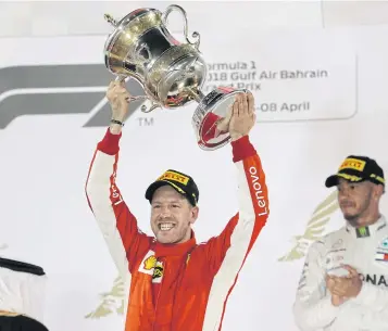  ?? AP ?? Ferrari’s Sebastian Vettel celebrates on the podium as Mercedes’ Lewis Hamilton looks on.