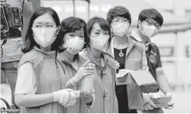  ?? Lee Jin-man / Associated Press ?? South Korean health workers, wearing masks as a precaution against the MERS virus, wait to check examinees’ temperatur­e and to sanitize their hands at a test site for a civil service examinatio­n in Seoul, South Korea, on Saturday.