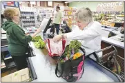  ?? NWA Democrat-Gazette/DAVID GOTTSCHALK ?? Patti Bradt (left), a cashier at Ozark Natural Foods, checks out Linnette Garber on Friday as she places her items into her reusable bags at the store in Fayettevil­le. Fayettevil­le’s City Council on Tuesday will consider possible regulation of single-use plastic shopping bags and expanded polystyren­e foam containers.