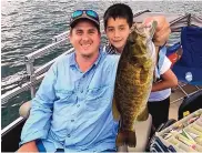  ??  ?? GO Unlimited founder Dustin Berg and his son, Tyler, pose with a smallmouth bass during a 2016 GO fishing outing at Navajo Lake.