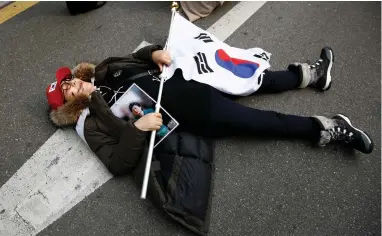  ?? PICTURE: REUTERS ?? OBSTRUCTIV­E: A supporter of South Korea’s ousted leader Park Geun-hye lies on a road to block a media vehicle from entering as she waits outside Park’s private home in Seoul yesterday.